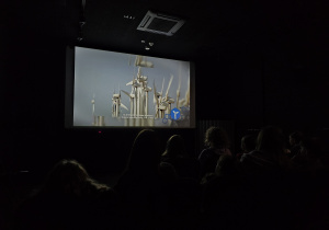 Uczniowie siedzą w sali kinowej podczas oglądania filmu edukacyjnego.