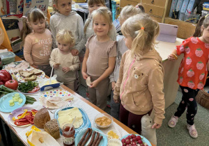 Dziewczynki stoją przy szwedzkim stole podczas zajęć o zdrowym odżywianiu.