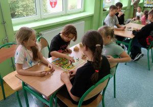 Dziewczynki i chłopcy grają w planszówki.