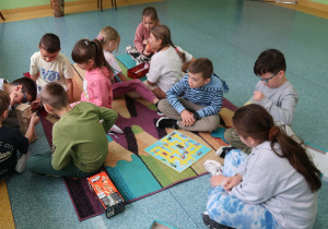 Uczniowie na korytarzu szkolnym grają w planszówki.