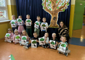 Grupa Promyczki prezentuje swoje prace wykonane techniką kolaż na korytarzu przedszkolnym w Dniu Drzewa.