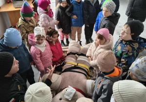 Przedszkolaki transportują Misia na desce ratunkowe.