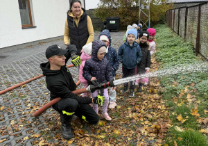 Dziewczynka z grupy Żabki próbuje swoich sił przy obsłudze węża gaśniczego.