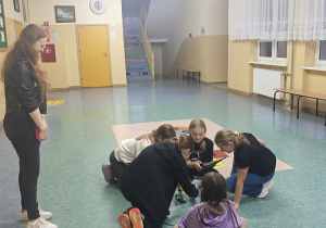 Pani prowadząca zajęcia z robotyki nadzoruje uczniów pracujących nad swoimi projektami.