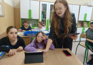Pani prowadząca przedstawia uczennicom możliwości programowania robotów.