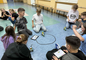 Uczniowie prezentują swoje sumoboty na korytarzu szkolnym.