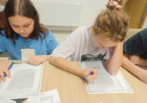 Uczniowie rozwiązują wykreślanki. Siedzą przy stolikach.