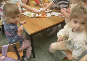 Dzieci z grupy Słoneczka jedzą przygotowane szaszłyki owocowo -warzywne.