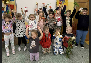 Dzieci z warzywami w rękach grupowo pozują do zdjęcia.