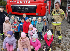 Zdjęcie grupowe Zuchów ze strażakami przed wozem strażackim.