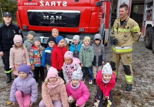Zdjęcie grupowe Zuchów ze strażakami przed wozem strażackim.