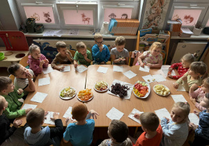 Dzieci z grupy Promyczki przy wspólnym stole degustują przyniesione owoce i warzywa.