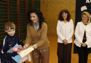 Pani Dyrektor wręcza nagrodę uczniowi kl, V za zajęcie I miejsca w ,,Konkursie Pięknego Czytania”. Obok stoi nauczyciel bibliotekarz i polonistka.
