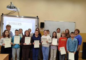 Uczestnicy ,,Konkursu Pięknego Czytania” stoją w klasie. W rękach trzymają dyplomy. Razem z uczniami jest Pani Kierownik Szkoły i Pani polonistka.