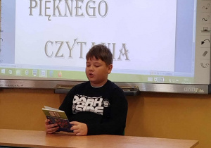 Uczeń kl. IV czyta fragment książki pt. ,,O psie, który jeździł koleją” Romana Pisarskiego.