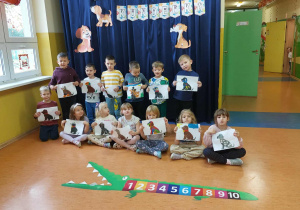 Zdjęcie grupowe dzieci z grupy Zuchy w Dniu Kundelka - przedszkolaki prezentują pieski wyklejone plasteliną.