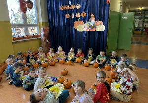 Promyczki siedzą w kole z dyniami.