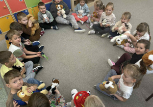 Dzieci w kole z pluszakami pieskami.