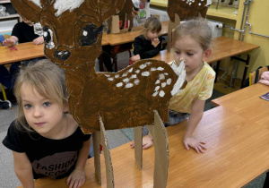 Dziewczynki z Grupy Żabki pozują do zdjęcia z sarenką którą pomalowały farbami.