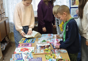 Uczniowie Szkoły Podstawowej w Rzeczycy oglądają książki w czasie Kiermaszu Książki.
