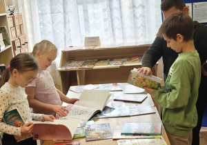 Uczniowie klas I-III wybierają książki do kupienia w czasie Kiermaszu Książki w Szkole Podstawowej w Rzeczycy.