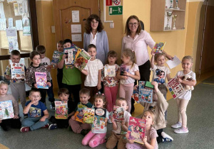 Przedszkolaki ze Szkoły Filialnej w Sadykierzu stoją przed biblioteką z zakupionymi książkami. Z przedszkolakami jest wychowawczyni i bibliotekarka.