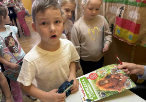 Przedszkolaki w Bibliotece Szkoły Filialnej w Sadykierzu. Uczeń trzyma portfel i czeka na sprawdzenie ceny książki. Za nim w kolejce stoją przedszkolaki ze swoimi wybranymi do kupienia książkami.