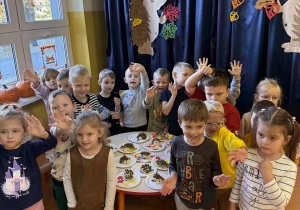 Zdjęcie grupowe przedszkolaków z grupy Promyczki wokół stolika, na którym prezentowane jeże z masy solnej.