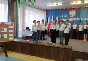 Uczniowie recytują wiersze i śpiewają piosenki patriotyczne.