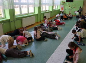 Korytarz szkolny wypełniony kolorującymi dziećmi.