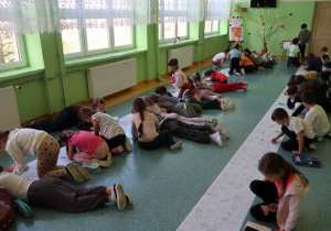 Korytarz szkolny wypełniony kolorującymi dziećmi.