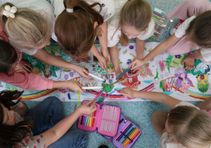 Uczennice malujące kredkami i mazakami elementy malowanki.