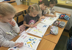 Dziewczynki siedzące przy stoliku i uzupełniające książki.