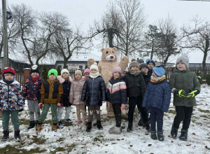 Grupowe zdjęcie dzieci z pluszowym misiem.