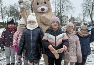 Dziewczynki z dużym pluszowym misiem na śniegu.