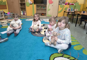 Dzieci z grupy Słoneczka z pluszakami siedzą na dywanie.