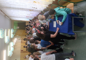 Korytarz szkolny wypełniony wróżącymi sobie uczniami.