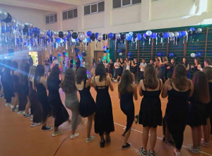 Uczennice klas VII - VIII tańczą wspólnie na sali w kółku.