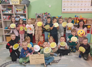 Przedszkolaki z grupy Zuchy prezentują swoje prace na dywanie w sali obok jest pedagog specjalny.