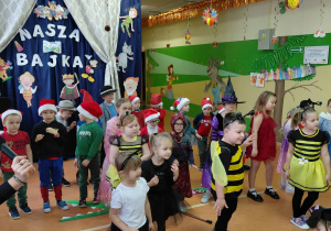 Dziewczynki w stroju Pszczółki Mai i chłopiec w stroju Gucia tańczą wraz z innymi dziećmi w tracie bajkowego występu.