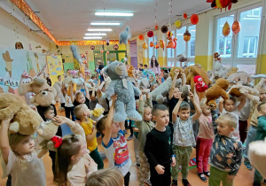 Dzieci ze wszystkich oddziałów przedszkolnych unoszą do góry swoje misie.