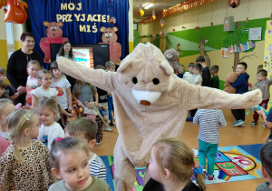 Miś Gregory tańczy w kole z dziećmi.