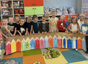 Dzieci z grupy „Promyczki” prezentują kolorowy płotek z kredek malowanych pastelami.