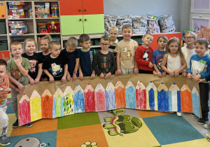 Dzieci z grupy „Promyczki” prezentują kolorowy płotek z kredek malowanych pastelami.