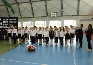 Uczniowie podczas śpiewania hymnu państwowego przy akompaniamencie granym na trąbkach przez dwie uczennice.