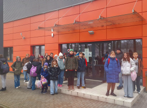 Grupa uczniów stoi przed krytą halą do siatkówki plażowej.