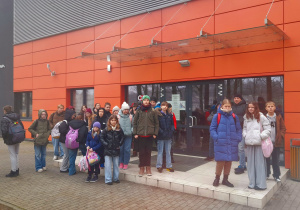 Grupa uczniów stoi przed krytą halą do siatkówki plażowej.