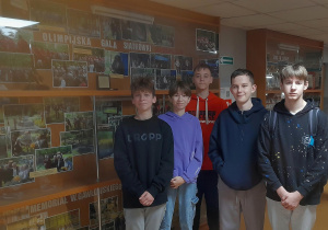 Uczniowie stoją przy olimpijskiej galerii siatkówki.