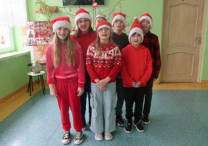 Uczniowie klasy czwartej prezentują czapki Mikołaja.