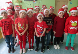 Uczniowie z klasy drugiej prezentują czerwone czapki Mikołaja.